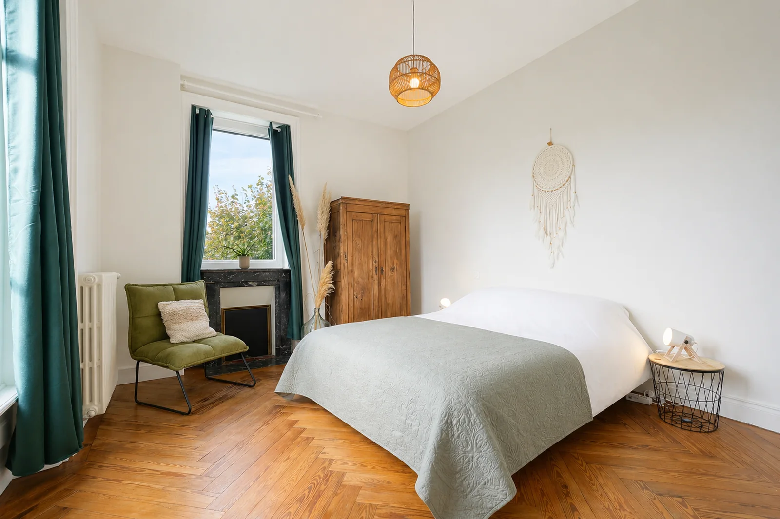 Bedroom at Le Manoir Ducey with fireplace, green armchair and parquet floors