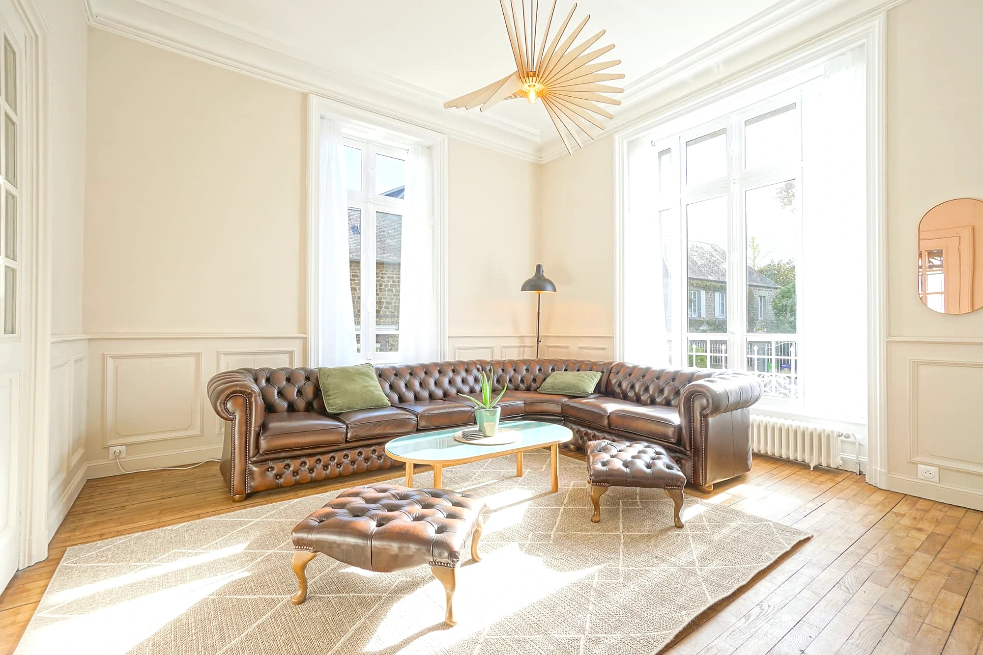 Light-filled drawing room at Le Manoir Ducey with a leather Chesterfield sofa