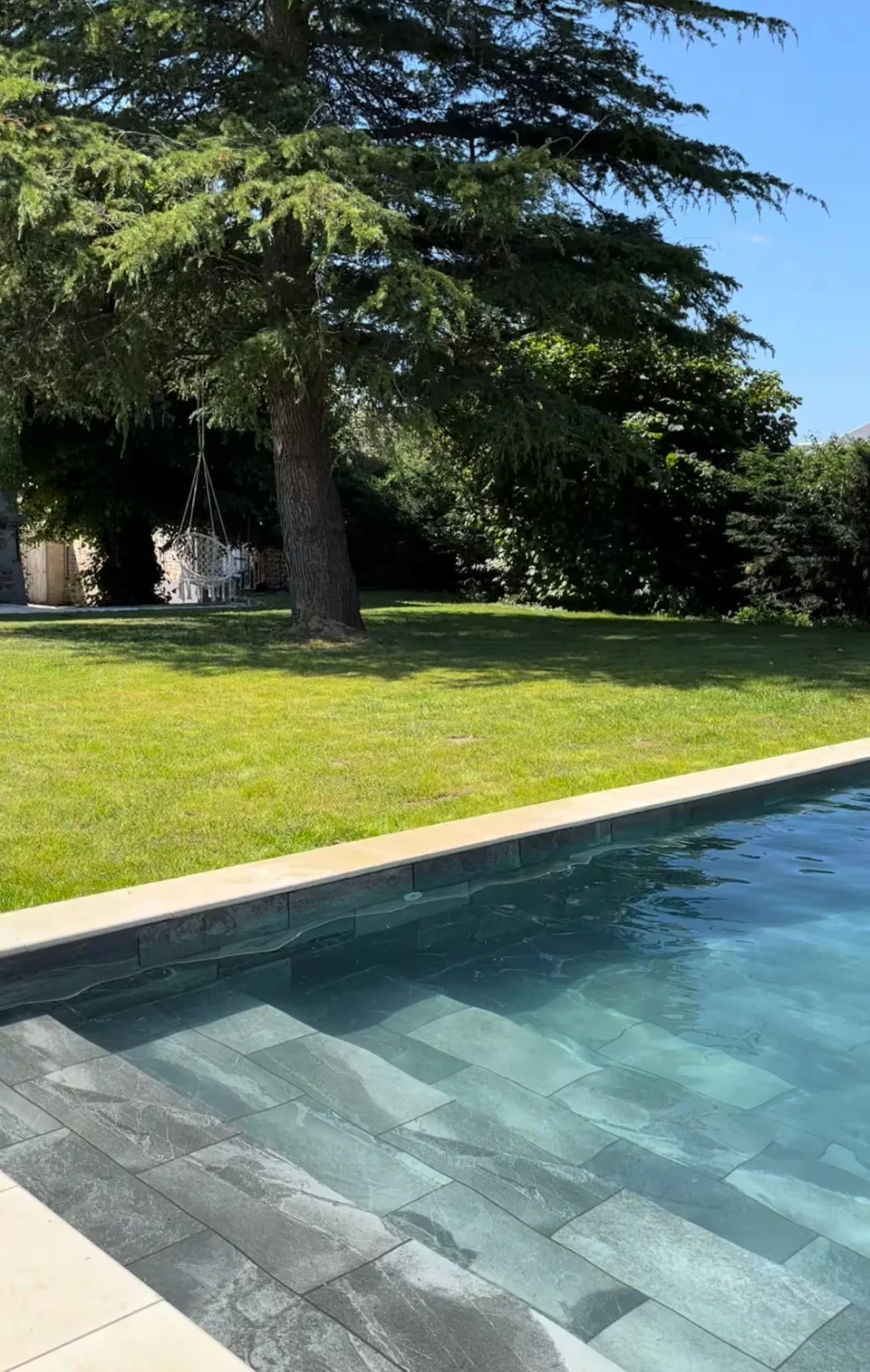 Mature cedar tree and lawn beside the swimming pool at Le Manoir Ducey