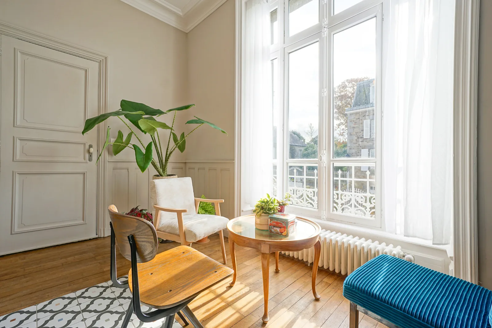 Quiet sitting corner by a tall window at Le Manoir Ducey, with morning light on the parquet